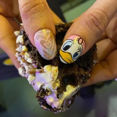 Chocolate waffle or nails? This fun design features a hand-painted Daisy Duck on one nail and a sparkling glitter heart on the other. A perfect treat for your fingertips.