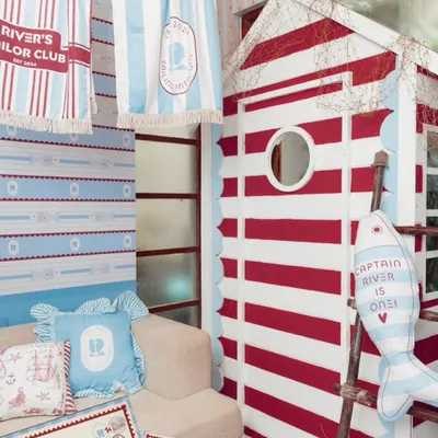 A cozy corner of the "River's Sailor Club" party, featuring a custom-built striped cabin, personalized pillows, and themed towels hanging on a line.