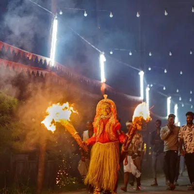 A Bhoota Kola performer emerges, holding two large flaming torches that light up the night. I use this natural, dramatic light to capture the spiritual power and intensity of the performance without disturbing the ritual.
