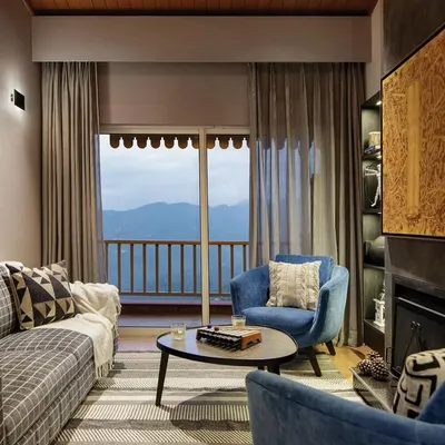 The living room is the soul of this mountain home, anchored by a hand-built fireplace and wrapped in the warmth of natural wood. We designed this space for pause and presence, with our signature Ava chairs inviting you to linger by the fire and soak in the snow-capped views.