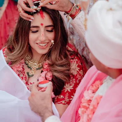 A sacred moment in a Hindu wedding ceremony, as the groom applies sindoor to the bride's forehead, symbolizing their new status as a married couple.