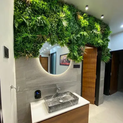 A unique bathroom vanity design featuring a vertical garden around a backlit circular mirror and a striking marble vessel sink.