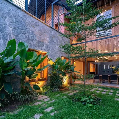 This internal courtyard is designed to be viewed from multiple rooms. It features a mix of natural stone, lush tropical plants like the Bird of Paradise, and a central tree, creating a private, tranquil garden within the home's walls.