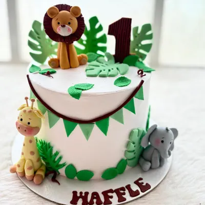 The jungle theme is one of my most popular requests for first birthdays. This cake features adorable, handmade fondant animals like a lion, giraffe, and elephant, surrounded by tropical leaves.