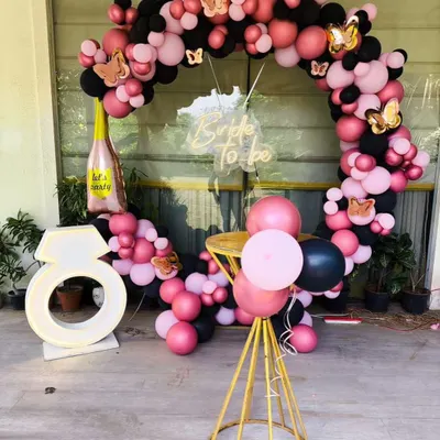 For this bride-to-be party, I created a full circular balloon arch in pink and black, accented with gold butterflies. The setup includes a custom 'Bride To be' neon sign and a large, illuminated ring prop for the perfect photo opportunity.