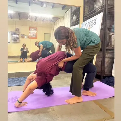 Providing hands-on assistance is key to safe practice. Here, I'm supporting a student in Wheel Pose to ensure her alignment is correct, preventing injury and helping her experience the full benefits of the asana.