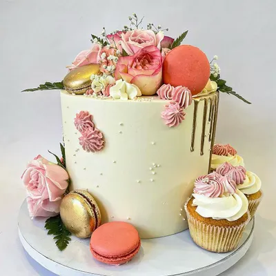 This is one of my favorite styles: simple, elegant, and unique. The tall buttercream cake is decorated with fresh pink roses, gold and pink macarons, a subtle gold drip, and coordinating cupcakes on the side.