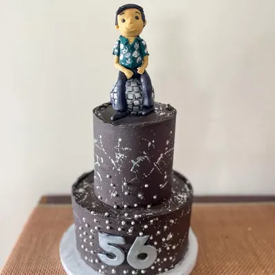 Time to boogie! This two-tiered disco-themed cake was for a 56th birthday party. It's covered in dark chocolate ganache with silver splatter and features a custom fondant figurine of the birthday guy on a disco ball.