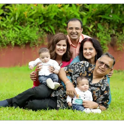 A multi-generational family portrait featuring grandparents, parents, and two young babies in a lush garden. We take pride in creating compositions that celebrate the entire family tree in a single, beautiful photograph.