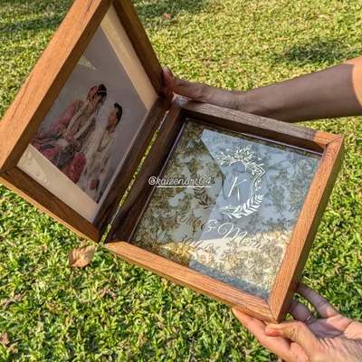 This is my folding teak wood box frame, a truly unique way to preserve your memories. One side holds a photo, and the other holds your wedding flowers preserved in resin with a custom monogram.
