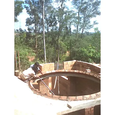 A mason skillfully constructing a circular brick dome for the Professor's Residence. This showcases the high level of craftsmanship involved in our projects and our use of traditional building techniques like domes and vaults.