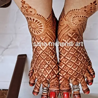 A full bridal foot mehendi with a rich, dark stain. The design features a detailed net pattern covering the entire foot.