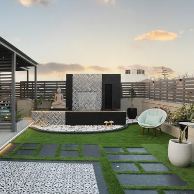 Peace and tranquility, right on your rooftop. This space features a modern water feature with a calming cascade, a serene Buddha statue, and a comfortable chair for quiet contemplation.