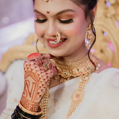 A detailed shot of the bride's hands, adorned with intricate mehndi and the groom's initial. This portrait highlights the beautiful jewelry and the traditional black bangles, capturing the essence of a Maharashtrian bride.