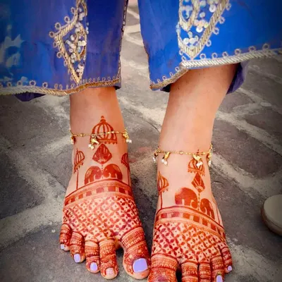 The beautiful dark stain of a bridal foot mehndi design. This pattern features traditional elephant and dome motifs with a delicate checkered pattern on the toes.