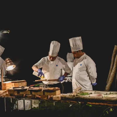 Our chefs are the heart of the experience, seen here preparing dishes at a live station. We go beyond standard counters to deliver extraordinary concepts like a Fromage Bar and modern Indian Wood-fired Kulchas.