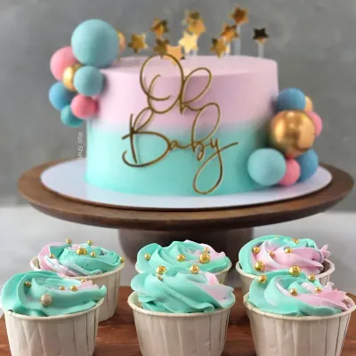 This "Oh Baby" shower cake is a perfect example of my custom, fondant-free work. The pastel pink and blue ombre effect is created with delicate whipped cream, complemented by matching cupcakes for a complete dessert table.