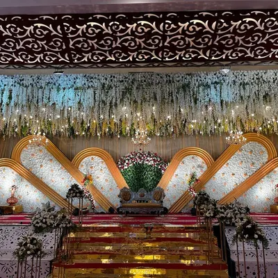 This grand reception stage in Hassan features a stunning backdrop made of thousands of white flowers. The design uses layered panels and a ceiling of hanging florals, all illuminated to create a truly luxurious and photogenic setting.