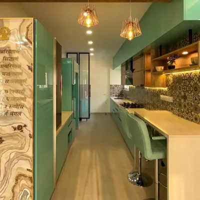 This parallel kitchen is designed for efficiency and style. The long countertop provides ample workspace, while the aqua cabinetry and patterned tiles add a burst of personality. All woodwork is BWP ply for maximum durability.