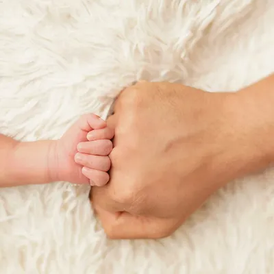 A newborn's tiny fist bumping their parent's. This powerful image symbolizes the immediate and strong connection between a parent and child.