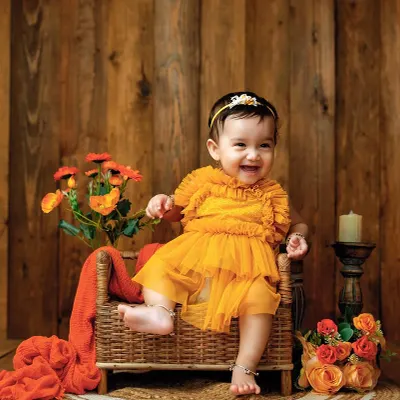 I love this warm, rustic setup. The rich tones of the wooden background and the bright orange dress make this little one's joyful smile pop.