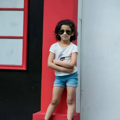 So much attitude in such a little person. We love this shot of a young girl posing with confidence and style against a bold red pillar in our outdoor studio space.