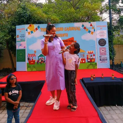 On stage at "The Weekend Carnival," sharing the mic with a confident young participant. I enjoy hosting community events that bring families and local talent together.