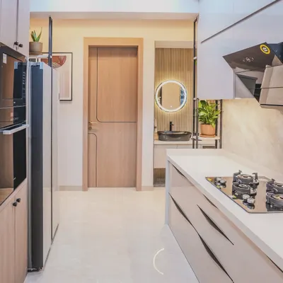 This sleek, modern kitchen at Sai World Empire features handleless cabinets and a clean, linear design. The layout provides a clear view into the wash area, which is designed with the same level of detail.
