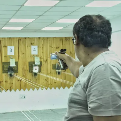 An adult participant takes aim with an air pistol down the 10m range. My sessions are open to everyone, regardless of prior experience.