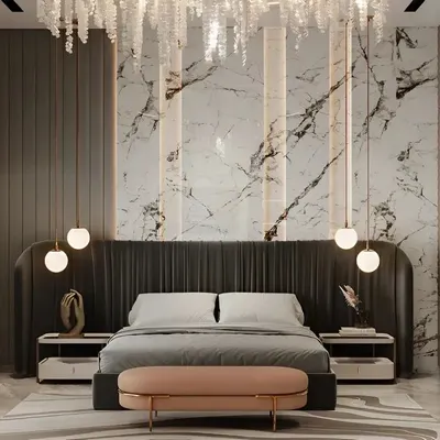 This master bedroom exudes luxury with a floor-to-ceiling marble accent wall and a dramatic crystal chandelier. The plush, oversized headboard and soft, ambient lighting from the hanging pendants create an atmosphere of pure indulgence and comfort.