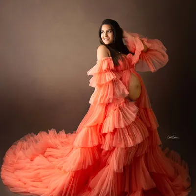 A truly showstopping maternity portrait. This mom-to-be looks radiant in a magnificent, multi-layered orange tulle gown that creates incredible texture and volume.