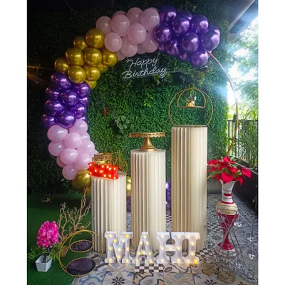 We combined natural and modern elements for this birthday setup. A lush greenery wall serves as the perfect base for a colorful balloon arch in purple, pink, and gold, complete with a neon sign and elegant pedestals for the cake.
