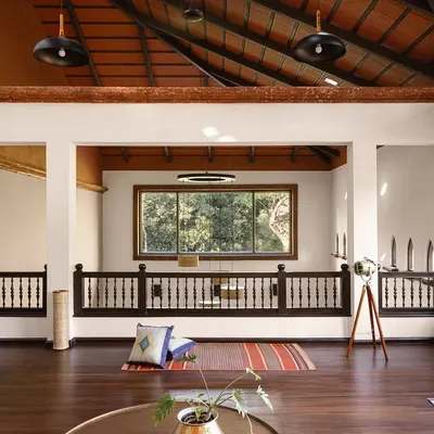 The wooden mezzanine lounge is a perch in the sky, offering a meditative seat to watch the seasons turn. The soaring terracotta-tiled roof and hand-turned balustrades frame the forest view, making the landscape a living part of the room.
