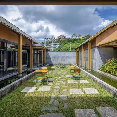 The central courtyard at Teyla, designed as a green lung for the cafe. The informal arrangement of stone pavers and outdoor seating encourages guests to relax and enjoy the open sky, surrounded by water channels and native plants.