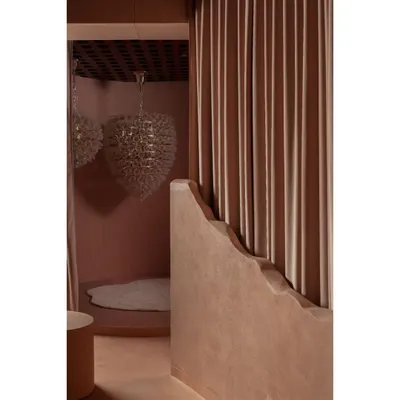 A glimpse into a moody, intimate corner of a showcase we designed. We used a rich, earthy pink tone throughout the space, complemented by a dramatic heart-shaped chandelier. The heavy curtain and curved wall create a sense of discovery as you move through the room.