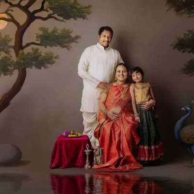 A regal family maternity portrait. The expecting mother is seated like royalty, surrounded by her family in a beautifully painted, traditional Indian setting.