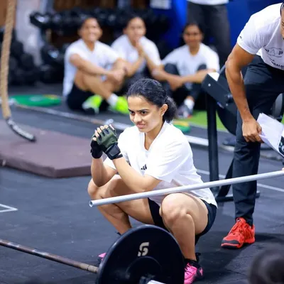 Even in a group setting, my focus is on individual form. Here, I'm guiding an athlete through a squat, ensuring her technique is precise before adding weight. Quality movement always comes first.