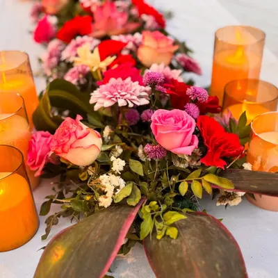 A close-up of a vibrant floral centerpiece surrounded by warm candlelight. These small arrangements on guest tables add color and elegance to the overall reception decor.