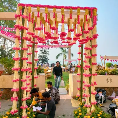 For this destination wedding, we created a stunning floral entryway with hanging garlands of pink and white flowers. Our team is on-site to ensure every petal is perfectly in place for the grand entrance.