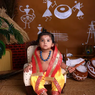 Your little one as the divine Bal Gopal. This Janmashtami setup features a traditional Warli art backdrop and a miniature throne, creating an authentic and charming portrait.