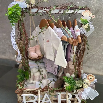 Our signature baby clothes hamper, creatively designed to resemble a miniature closet. This jungle-themed version features tiny hangers with baby outfits, booties, and plush toys, all nestled in a rustic, vine-adorned basket.