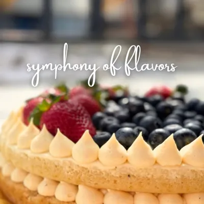 A symphony of flavors, this cake features two layers of light sponge with a creamy filling, piped details, and a generous topping of fresh strawberries and blueberries. It's a celebration of fresh, natural sweetness.