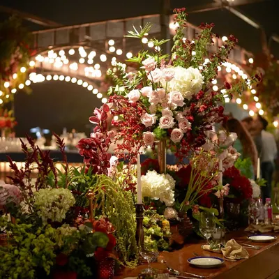 A stunningly opulent tablescape featuring a symphony of lush florals in deep reds and soft pinks. The warm glow of candles and gold accents brought an old-world charm to this enchanting dinner setting.