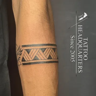A classic tribal armband tattoo with a woven pattern, showcasing clean lines and solid black fill.