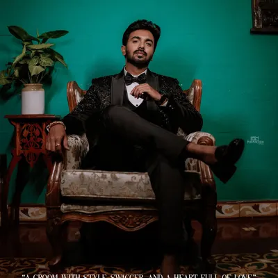 A stylish portrait of the groom seated in a vintage chair, looking sharp in his reception tuxedo.