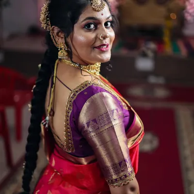 A classic bridal portrait showing the intricate details of the blouse, gold jewelry, and traditional braided hairstyle. This over-the-shoulder pose is timeless and elegant.