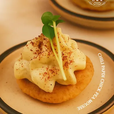 A perfect fusion of textures and tastes. Our Chilli Papdi with Chickpea Mousse is a signature creation, offering a modern gourmet twist on a traditional Indian cracker.