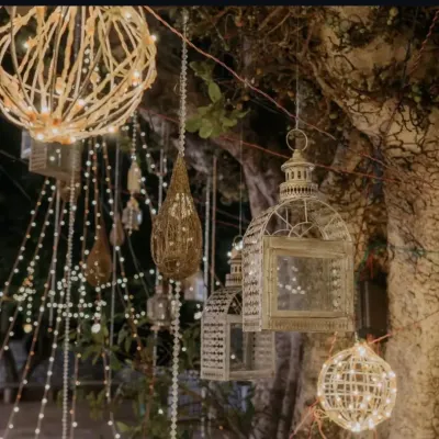 We use a variety of lighting elements, like these hanging lanterns and fairy lights, to create a warm and enchanting ambiance for evening events. This type of decorative lighting is perfect for outdoor or rustic-themed gatherings.
