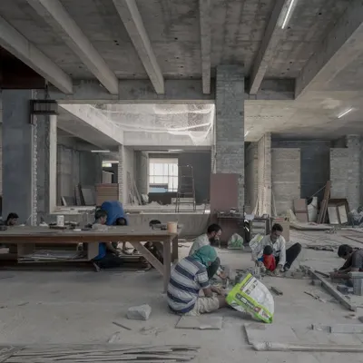 The Courtyard House in Hyderabad during construction. It's a moment of organized chaos as craftspeople work on the flooring, bringing the raw concrete structure to life.