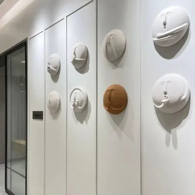 Art can be integrated directly into your walls. This hallway features a unique installation of quirky, 3D clay faces, turning a simple passage into a gallery of conversation-starting art.